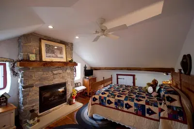 a bedroom with a bed and a stone fireplace at Osceola Mill House Bed and Breakfast in Gordonville