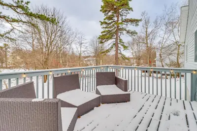 a balcony with two chairs and a table in the snow at Chic Pocono Hideaway with Private Indoor Sauna in Long Pond