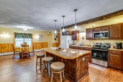 a kitchen with wooden cabinets and a kitchen island with bar stools at Lisle Apt 4 Mi to Dorchester Lake! in Lisle