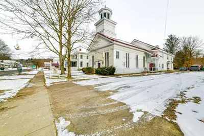 a white church with a steeple on a snowy street at Lisle Apt 4 Mi to Dorchester Lake! in Lisle