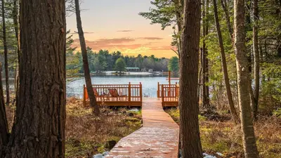 a wooden bridge over a lake in the woods at Lakeview Sunset Heaven by AvantStay Waterfront Home • Hot Tub Game Room Discounted Ski Tickets in Blakeslee