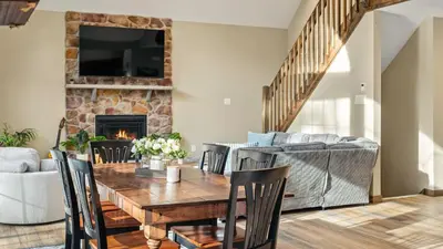 a living room with a wooden table and a fireplace at Lakeview Sunset Heaven by AvantStay Waterfront Home • Hot Tub Game Room Discounted Ski Tickets in Blakeslee