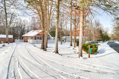 a snow covered street with trees and a house at 8 Mi to Big Boulder Mountain Cabin with Decks! in Albrightsville