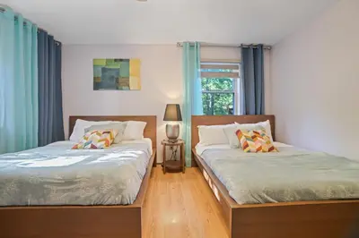 two beds in a bedroom with blue curtains at 5 Bedroom Cozy Retreat Lakefront in Mount Zion
