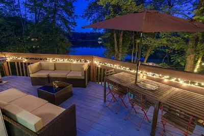 a deck with a table and chairs and lights at 5 Bedroom Cozy Retreat Lakefront in Mount Zion