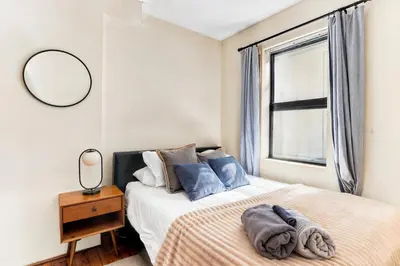 a bedroom with a bed with a mirror and a window at Stylish 2 Bedroom Apartment in Chelsea in New York