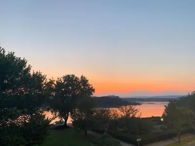 a sunset over a body of water with trees at BurgBnB Riverfront in Harrisburg