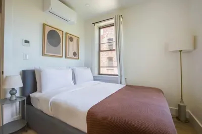 a bedroom with a large bed and a window at Blueground E Village rooftop pool gym ac NYC-1533 in New York