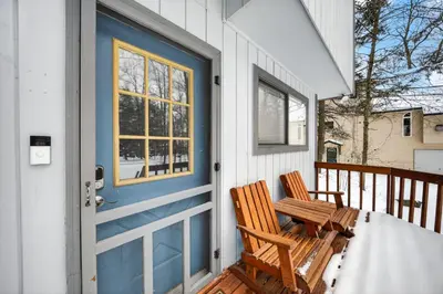 a porch with a blue door and a wooden chair at Peaceful Arrowhead Lakes Getaway Perfect for Spring and Summer Hot Tub Deck 3BR Home in Thornhurst