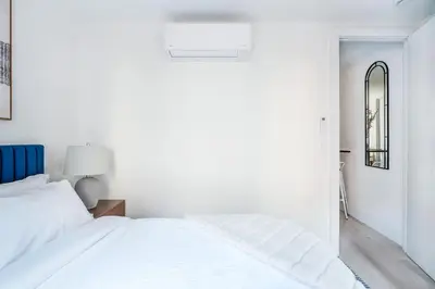 a white bedroom with a bed and a mirror at 48-3FE 2BR Prime Midtown West in New York
