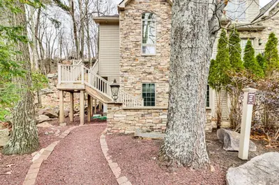 a stone house with a staircase leading up to a tree at Boulder Lake Access Townhome with Deck! in Lake Harmony
