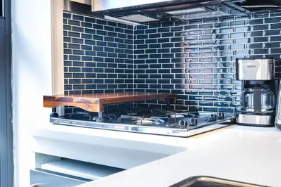 a stove top in a kitchen with blue tiles at 69-5C Festive Comfort Brand New 1BR Lower East Side Christmas Ready in New York