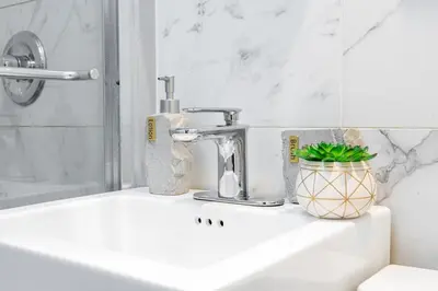 a bathroom sink with a faucet and a plant on it at 69-5C Festive Comfort Brand New 1BR Lower East Side Christmas Ready in New York