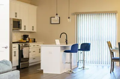 a kitchen with white cabinets and blue bar stools at Hidden Gem 2 in Norristown