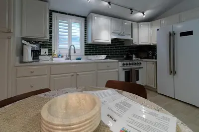 a kitchen with a table and a white refrigerator at Quiet Cottage In The Woods, with Hot Tub! in Glenmoore