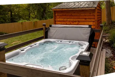 a hot tub in front of a wooden house at Quiet Cottage In The Woods, with Hot Tub! in Glenmoore