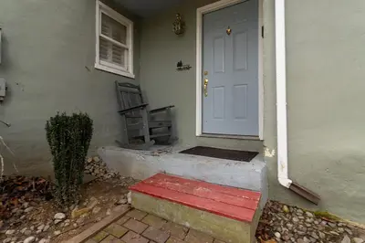 a door to a house with a red bench next to it at Quiet Cottage In The Woods, with Hot Tub! in Glenmoore