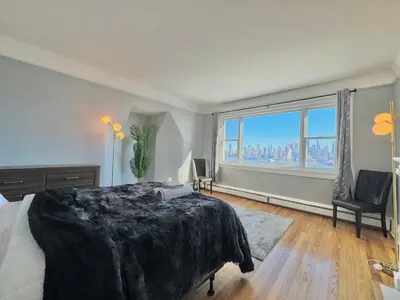 a bedroom with a large bed and a large window at Waterfront NYC skyline views in Union City