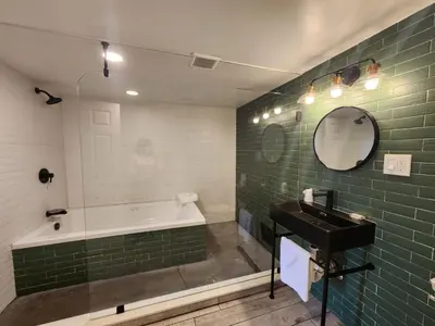 a bathroom with a tub and a sink and green tile at Westview Motel in North Bergen