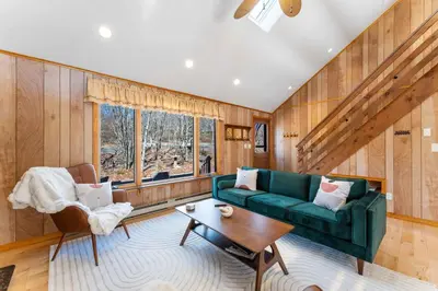 a living room with a green couch and a table at 4 Br Mtn Cabin Sauna Hot Tub Fire Pit Putt Putt in Albrightsville