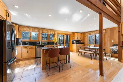 a kitchen with wooden cabinets and a island with bar stools at 4 Br Mtn Cabin Sauna Hot Tub Fire Pit Putt Putt in Albrightsville