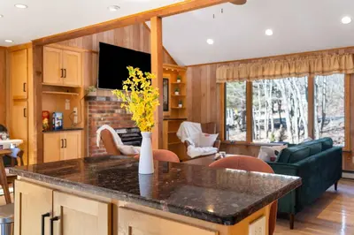 a kitchen with a counter top and a living room at 4 Br Mtn Cabin Sauna Hot Tub Fire Pit Putt Putt in Albrightsville
