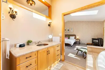 a bathroom with a sink and a bedroom with a bed at 4 Br Mtn Cabin Sauna Hot Tub Fire Pit Putt Putt in Albrightsville