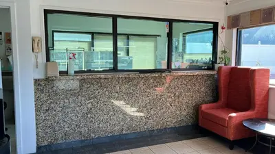 a bar with two red chairs and a window at Winslow Motel in Lyndhurst