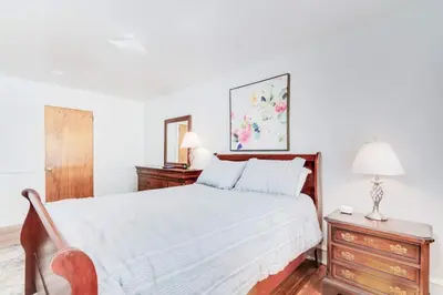 a bedroom with a white bed and a wooden dresser at Colleges Bistros History Come See The Main Line in Bryn Mawr