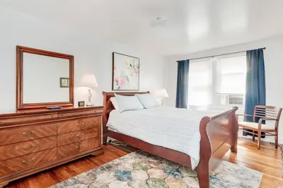 a bedroom with a bed and a dresser and a mirror at Colleges Bistros History Come See The Main Line in Bryn Mawr