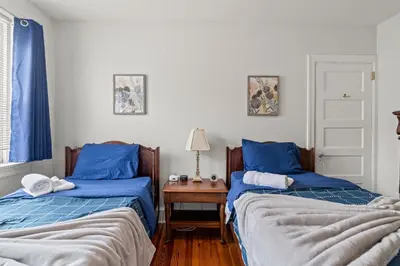a bedroom with two beds and a table with a lamp at Bryn Mawr GemBalconyDedicated Parking50TV in Bryn Mawr