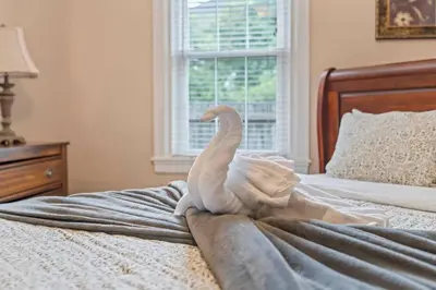 a white swan sitting on top of a bed at Stay At Our Tasteful, Private, & Elegant Abode in Devon