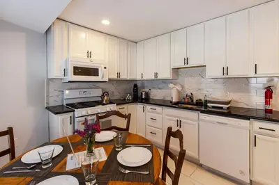 a kitchen with white cabinets and a table with chairs at Devon - Horse Show, History, Walk to Shops, Café's in Devon