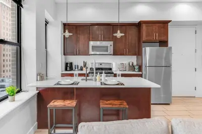 a kitchen with wooden cabinets and a stainless steel refrigerator at 20 MIN to Manhattan! 2BR Luxurious Comfy & Spotless in Newark