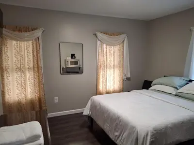 a bedroom with a bed and a mirror and curtains at Two-Bedroom Home Private Parking 25 min to NYC in Teaneck