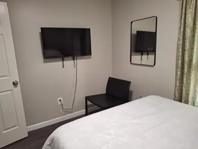 a bedroom with a bed and a chair and a television at Two-Bedroom Home Private Parking 25 min to NYC in Teaneck