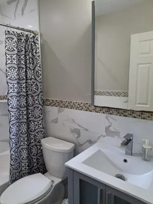 a bathroom with a toilet and a sink and a mirror at Two-Bedroom Home Private Parking 25 min to NYC in Teaneck