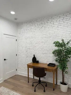 an office with a wooden desk and a white brick wall at Sustainable Apartment In University City in Philadelphia