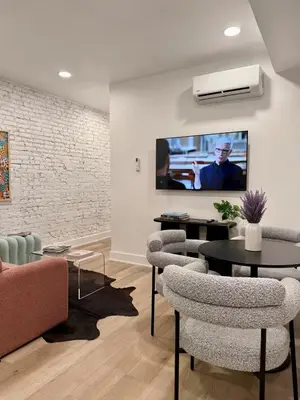 a living room with chairs and a tv on the wall at Sustainable Apartment In University City in Philadelphia
