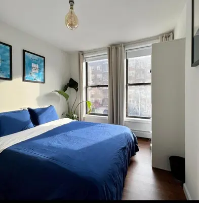 a bedroom with a blue bed and two windows at Chelsea Gem Modern 2BR Apt Prime 23rd & 7th Spot in New York