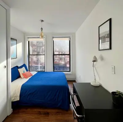 a bedroom with a blue bed and two windows at Chelsea Gem Modern 2BR Apt Prime 23rd & 7th Spot in New York