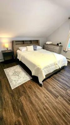 a bedroom with a large bed and a wooden floor at Friendly Home Near NYC in Little Ferry