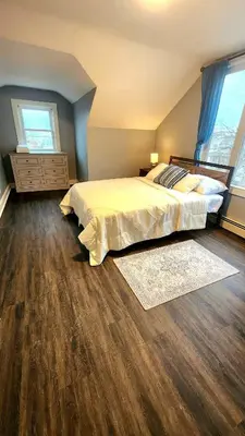 a bedroom with a large bed and wooden floors at Friendly Home Near NYC in Little Ferry