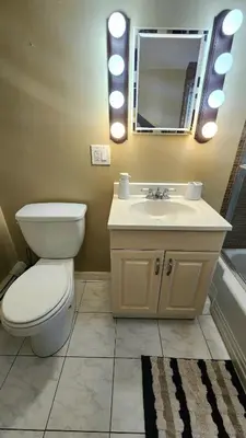 a bathroom with a toilet and a sink and a mirror at Friendly Home Near NYC in Little Ferry