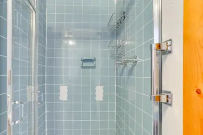 a bathroom with a shower with blue tiles at Waterfront Home on White Lake Near Bethel Woods! in White Lake