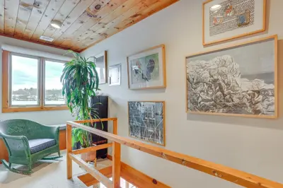 a living room with a green chair and pictures on the wall at Waterfront Home on White Lake Near Bethel Woods! in White Lake