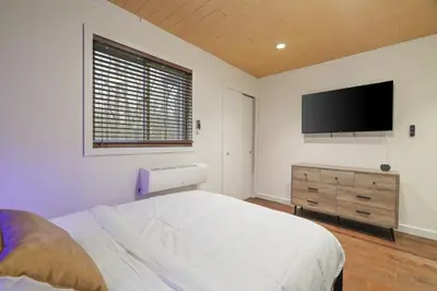 a bedroom with a bed and a flat screen tv at Luxurious Poconos Retreat - Hot Tub, Sauna, Games in East Stroudsburg