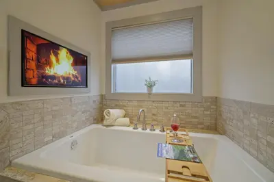 a bathroom with a large tub with a fireplace at Luxurious Poconos Retreat - Hot Tub, Sauna, Games in East Stroudsburg
