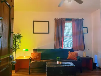 a living room with a green couch and a window at Ironbound 4 bdrm Industrial Suite! FREE parking in Newark