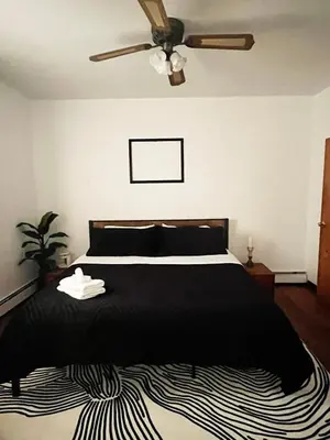 a bedroom with a black bed and a ceiling fan at Ironbound 4 bdrm Industrial Suite! FREE parking in Newark